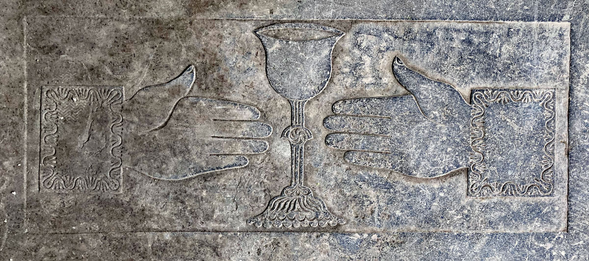 A pair of hands and a chalie carved on a tombstone within the cloisters of Sligo Dominican Friary.