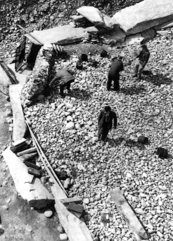 Workmen during the excavations at Newgrange, shortly before the roofbox structure was dismantled. Note the kerbstone which has fallen forwards due to cairn collapse.