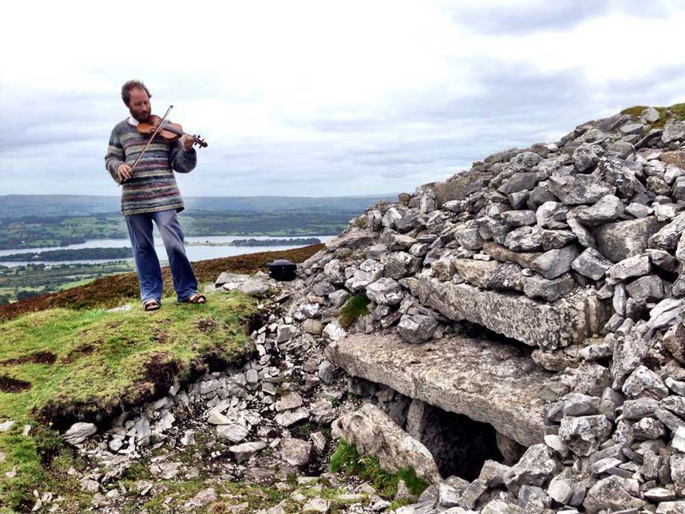 Tour Guide Martin Byrne fiddling at the roofbox he discovered at Cairn G in Carrowkeel.