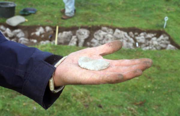 A flint knife, freshly excavated from the trench in the background.