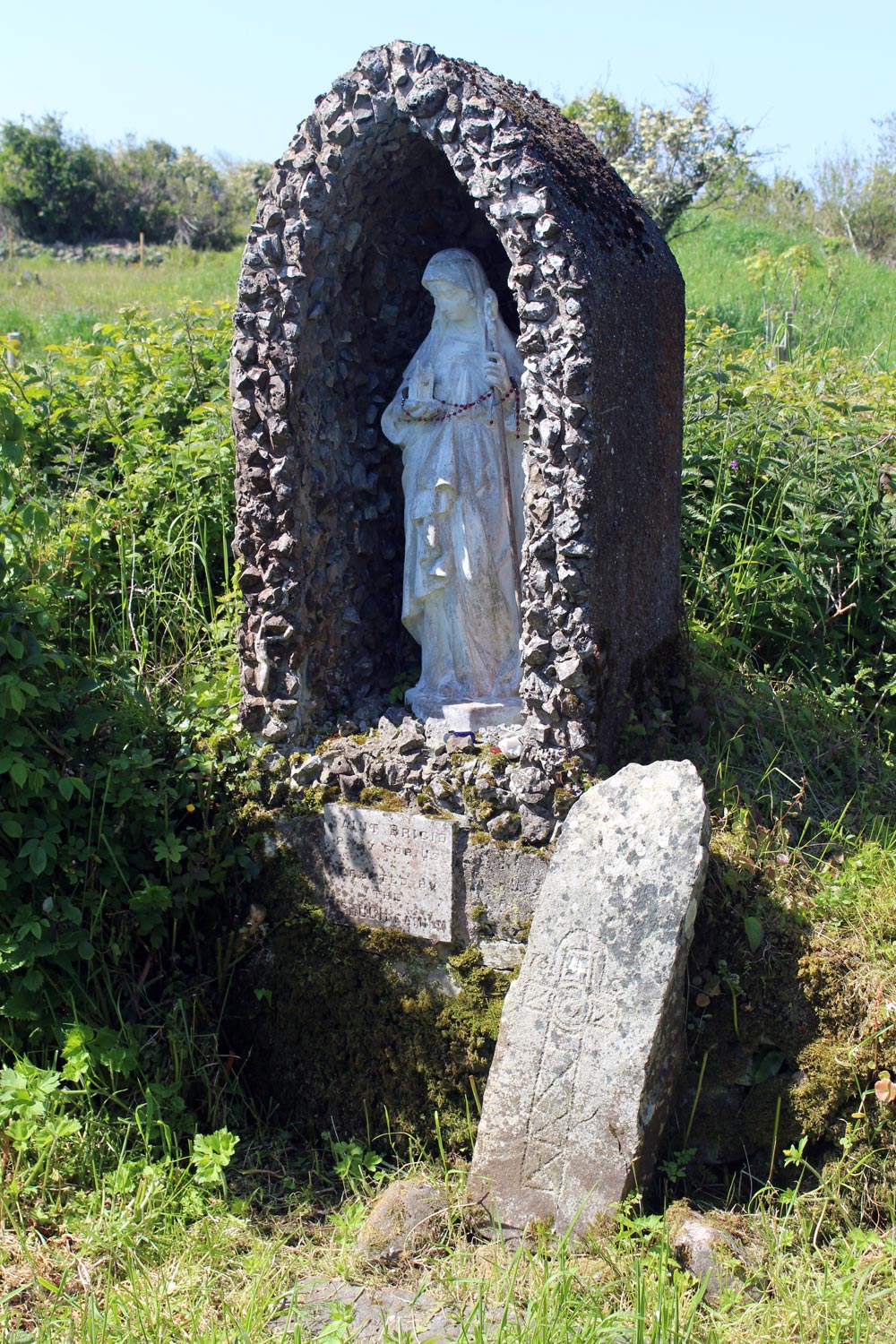 The early Christian cross-slab and modern statue of Saint Bridget.